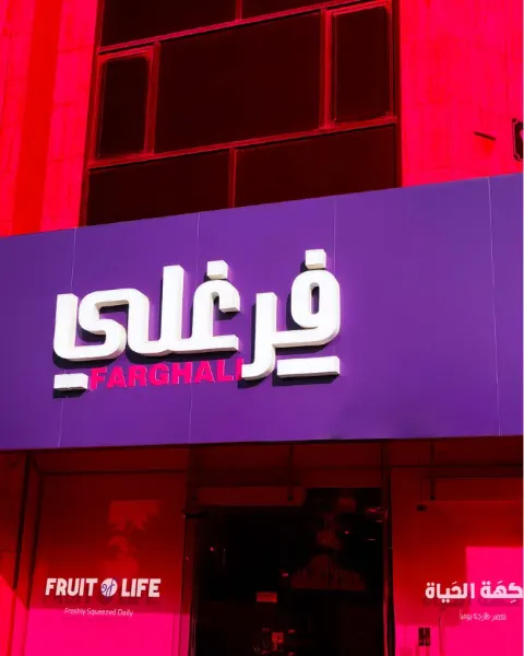 A Farghali juice center storefront with its illuminated purple sign