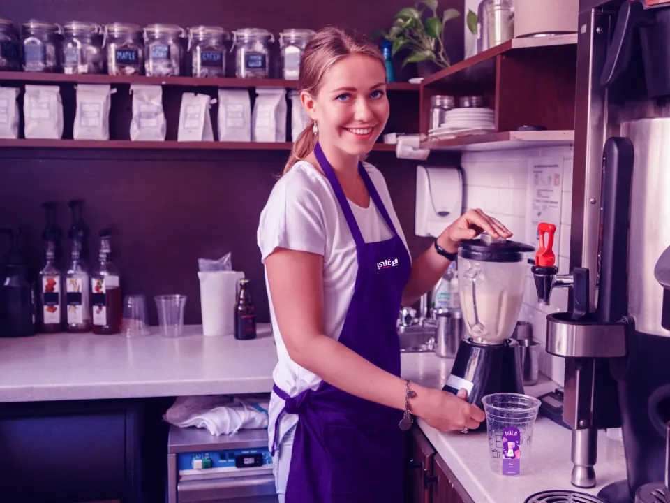 A Farghali team member in a branded apron preparing fresh juice behind the counter